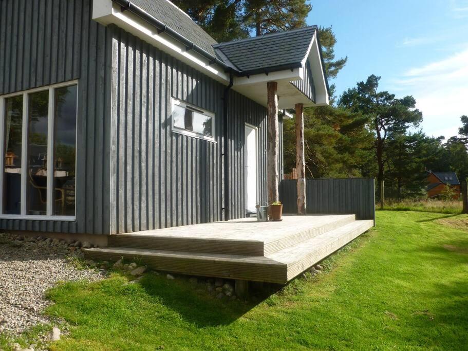 a small black house with a wooden porch at The Bothy, Nethy Bridge in Nethy Bridge