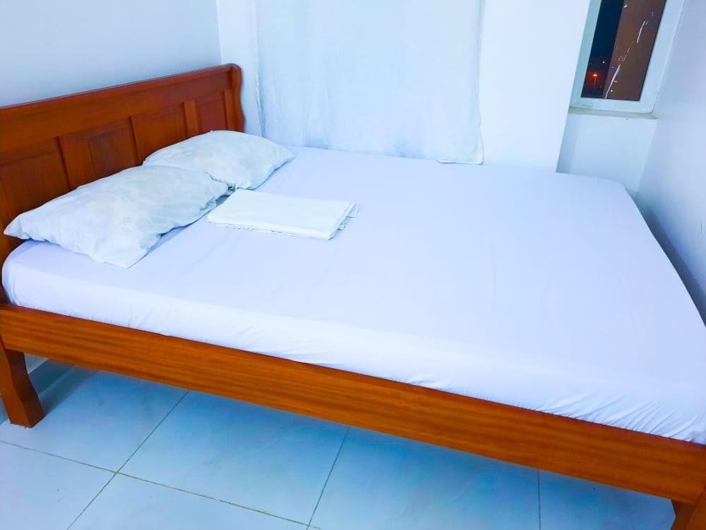 een bed met witte lakens en een papier erop bij Studio at Kisimani Heights Apartment. in Mombasa