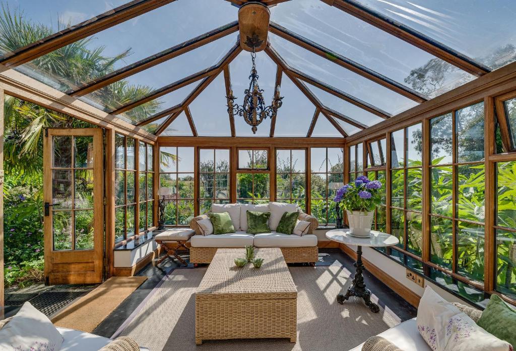 a conservatory with a chandelier and a room with windows at Tregadjack Farmhouse in Crowan
