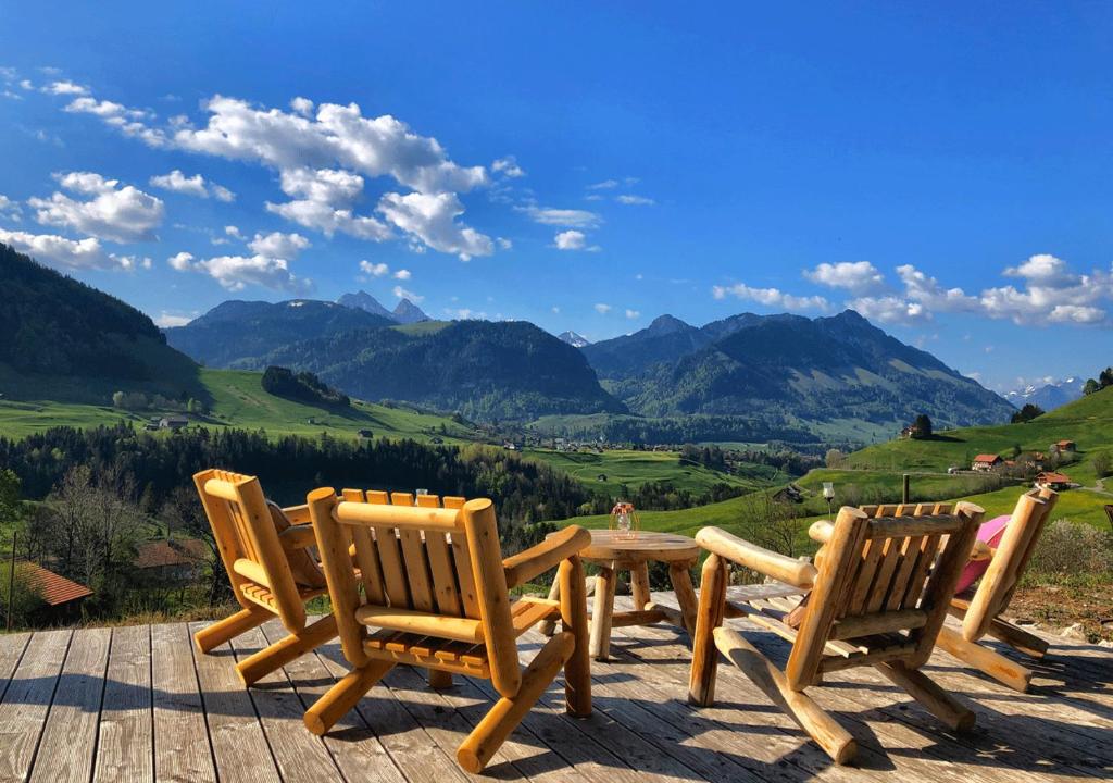 una mesa y sillas en una terraza con vistas a las montañas en Chalet authentique avec magnifique vue en Cerniat