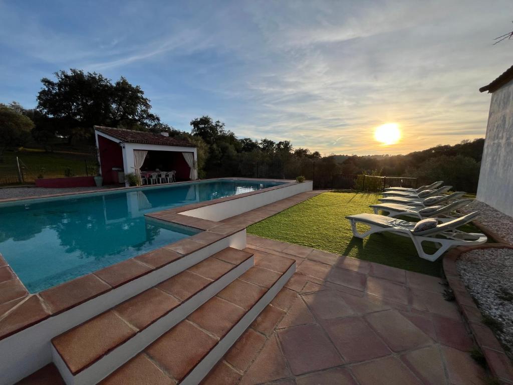 a swimming pool with a group of lounge chairs around it at CORTIJO RURAL FLOR DE CAZALLA in Cazalla de la Sierra