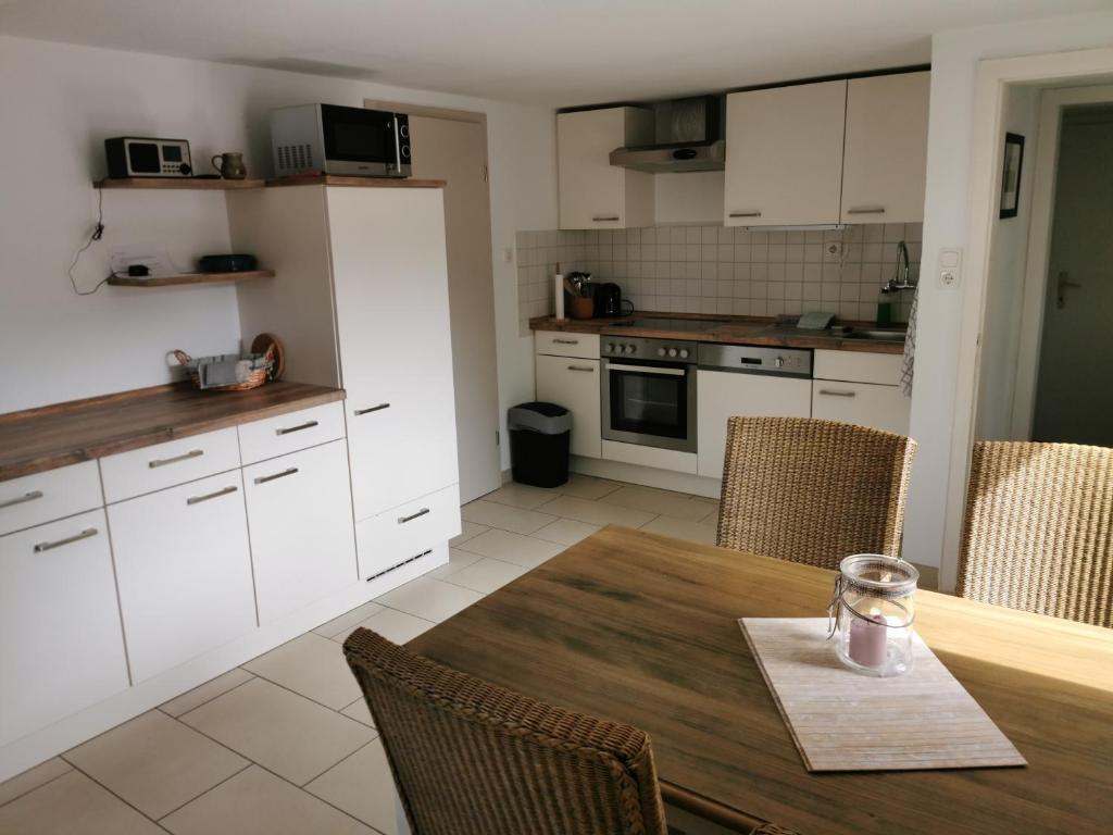 een keuken met een houten tafel en witte kasten bij Ferienhaus Franken Weinparadies in Obernbreit