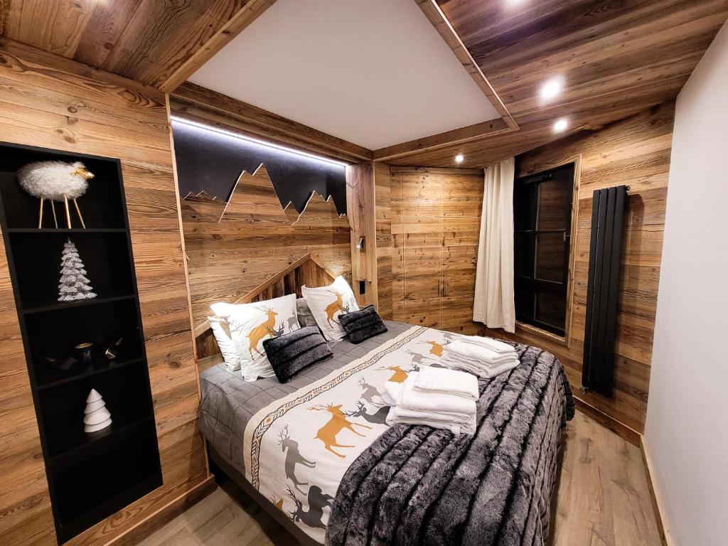 ein Schlafzimmer mit einem Bett in einem Zimmer mit Holzwänden in der Unterkunft LES ARCS Appartement Prestige Ski In Ski Out in Bourg-Saint-Maurice