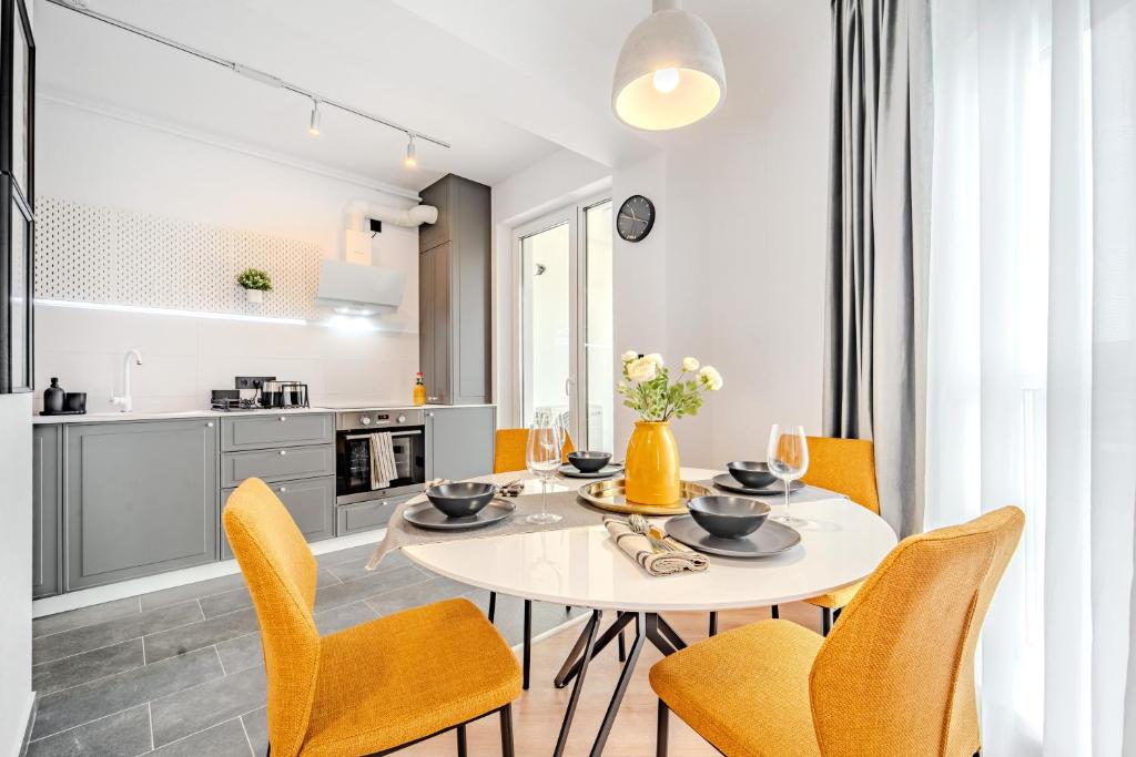 a kitchen and dining room with a white table and chairs at Smart Home - Gloria Apartment by Avenue in Timişoara