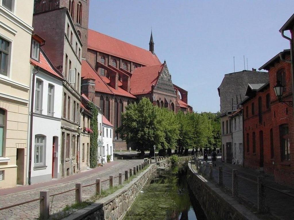 ein Kanal in einer Stadt mit Gebäuden und einer Straße in der Unterkunft Luv an der Nikolaikirche - ABC85 in Wismar