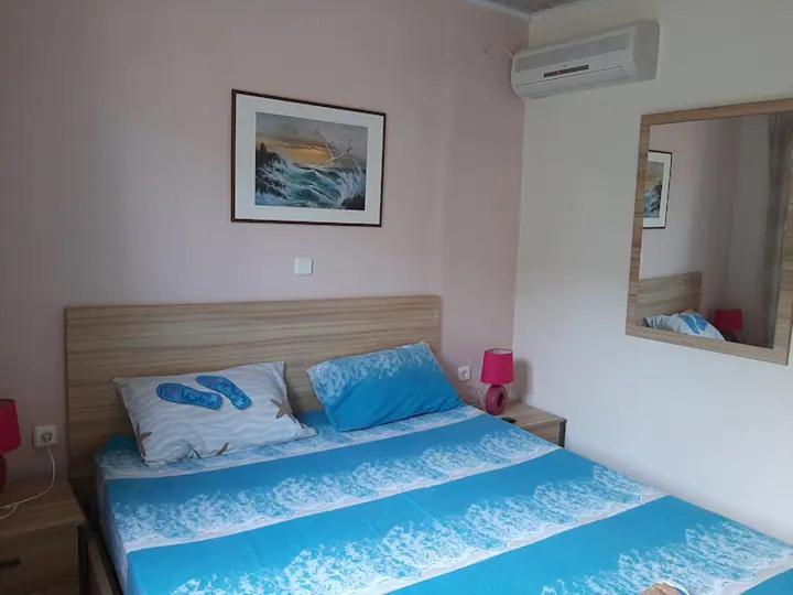 1 dormitorio con 1 cama con sábanas azules y espejo en Christina Apartment en Ágios Konstantínos