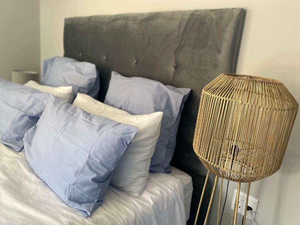 a bed with blue and white pillows and a lamp at Rollers Rest Guesthouse in Boksburg