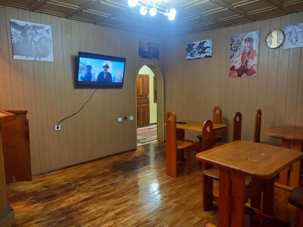een eetkamer met een tafel en een tv aan de muur bij ХОСТЕЛ FRIENDS in Karakol