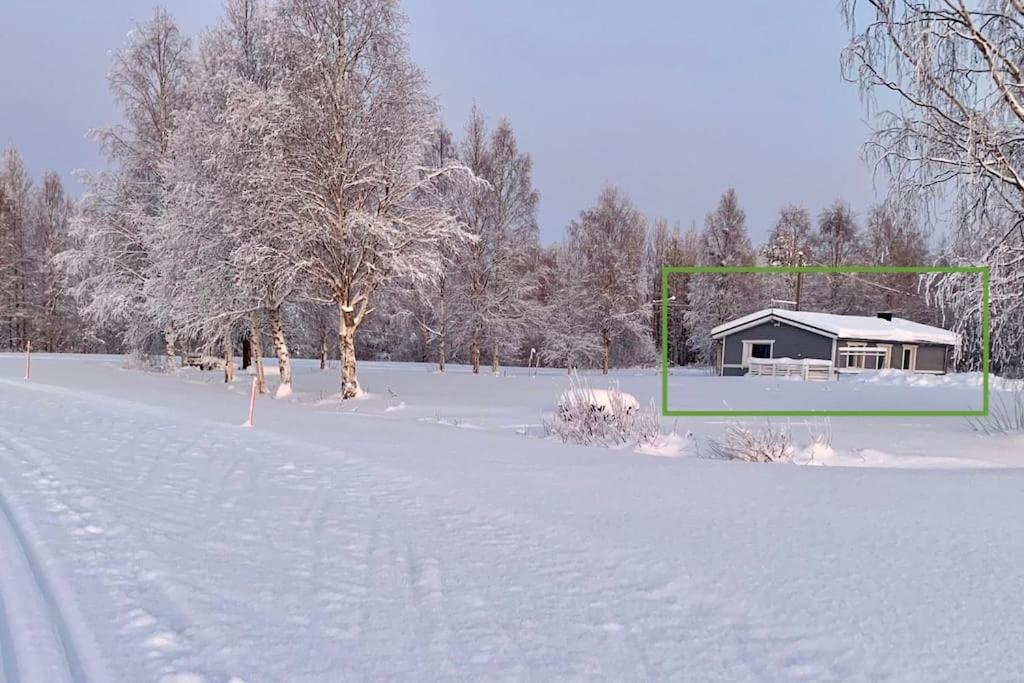 a snow covered field with a house and a goal at Viihtyisä mökki luonnonhelmassa 