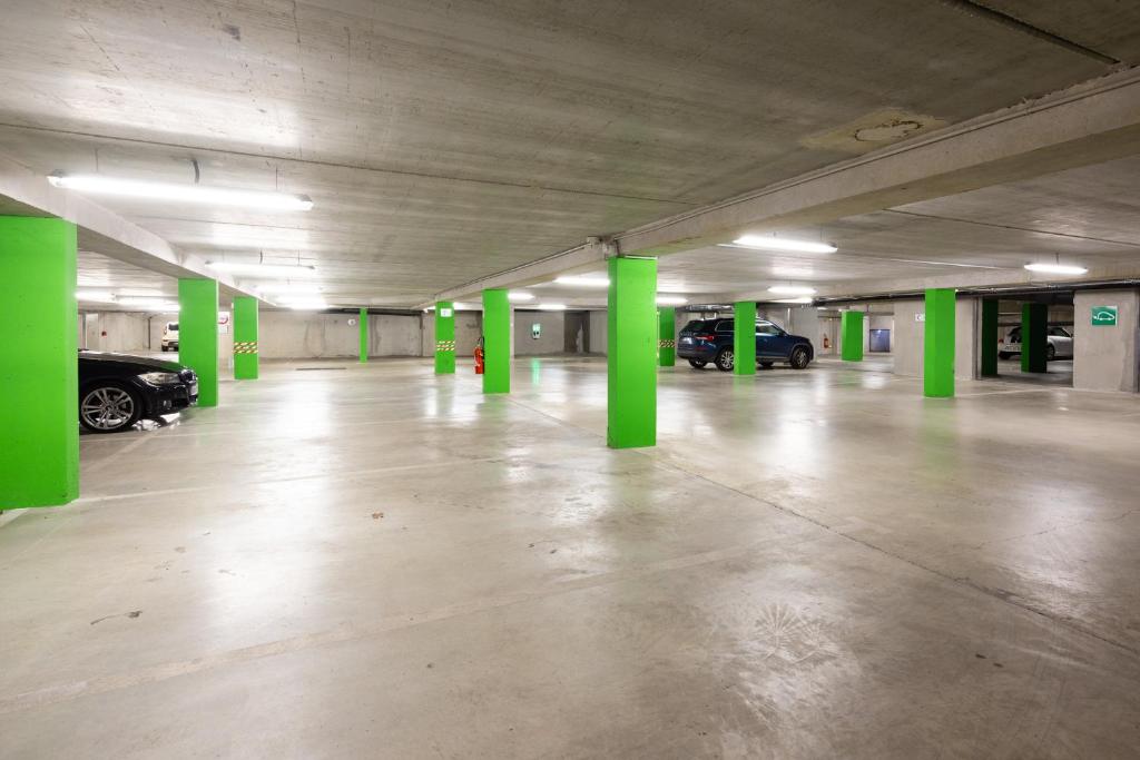 an empty parking garage with green columns and cars at Campanile Limoges Centre - Gare in Limoges