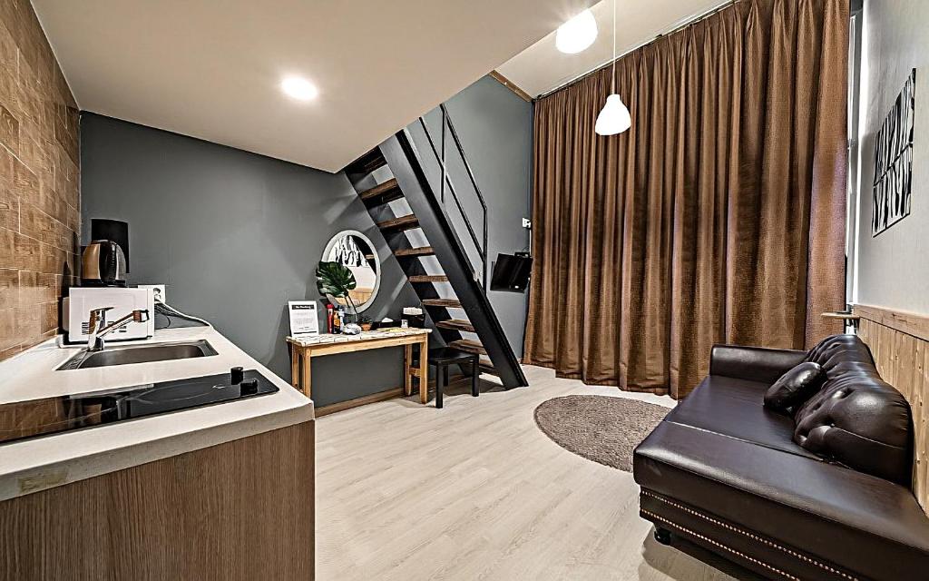 Hotel Hue Loft في انشيون: غرفة معيشة مع أريكة جلدية سوداء ودرج