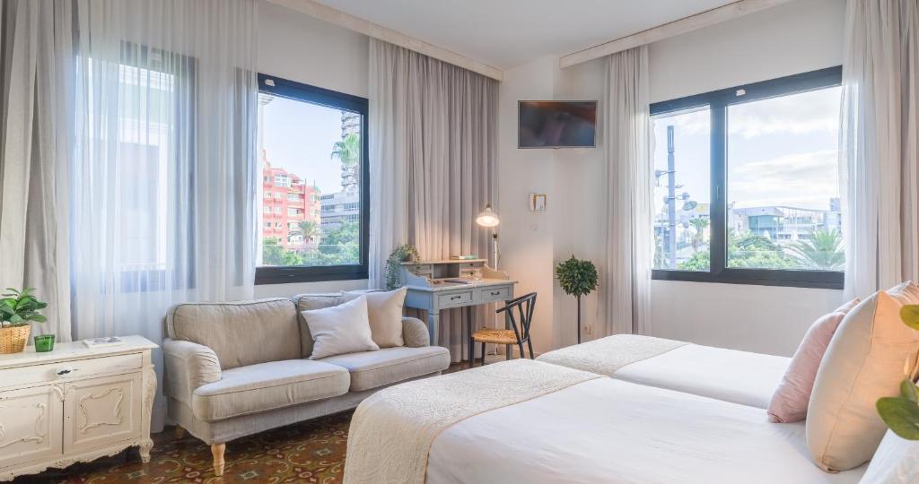 a hotel room with a bed and a chair and windows at Bed and Chic in Las Palmas de Gran Canaria