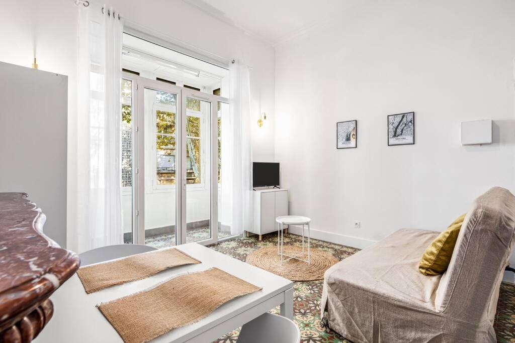 een witte woonkamer met een bank en een tafel bij 4 - Centre historique - patio - clim in Perpignan