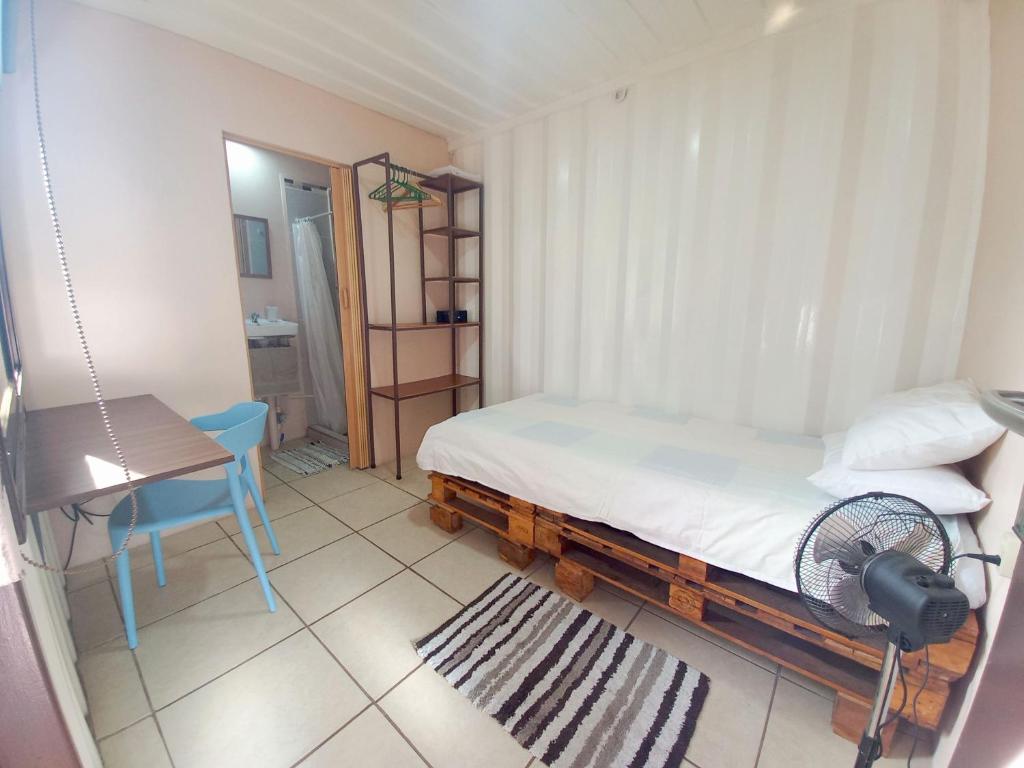 Schlafzimmer mit einem Bett, einem Tisch und einem Ventilator in der Unterkunft Costa Rica Eco-Container Hotel in Alajuelita