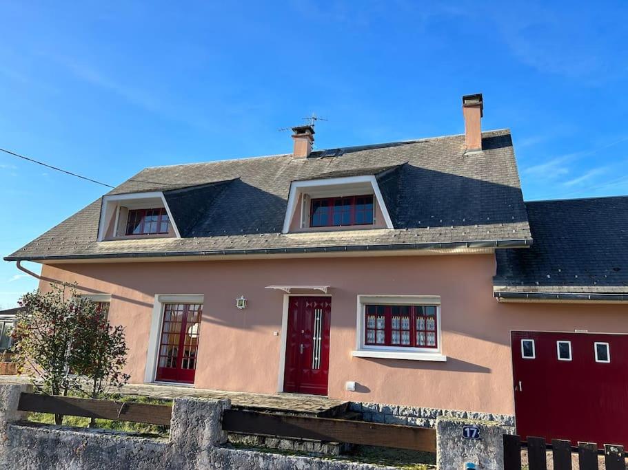 ein Haus mit roten Türen und einem grauen Dach in der Unterkunft Gîte LA MAISON ROSE in Lannemezan