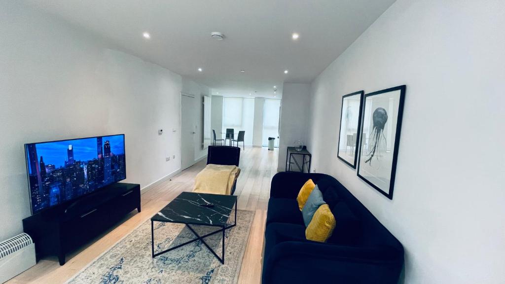 a living room with a blue couch and a tv at 2 BED 4 ADULTS IN ROYAL WHARF in London