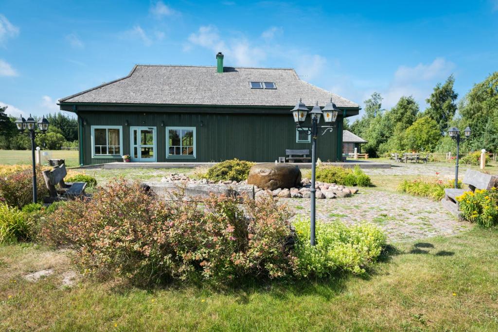 una pequeña casa verde con un jardín delante de ella en Pūķarags brīvdienu māja, en Pape