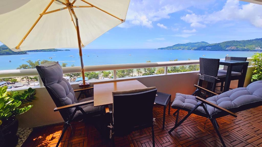 een balkon met stoelen, een tafel en een parasol bij Patong Tower Cozy Comfy Luxury Apartment with Seaview, for 1-3 people, in Phuket in Patong Beach