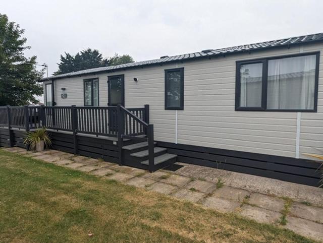 a small house with a porch and a deck at BEAUTIFUL LODGE on SHOREFIELD Country Park on edge of New Forest ENTERTAINMENT AND LEISURE PASSES INCLUDED in Milford on Sea