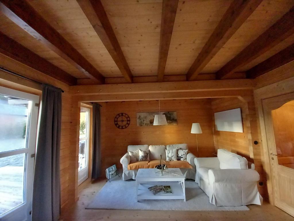 un soggiorno con mobili bianchi e soffitto in legno di Gemütliches Holzhaus in Gamlitz! a Gamlitz