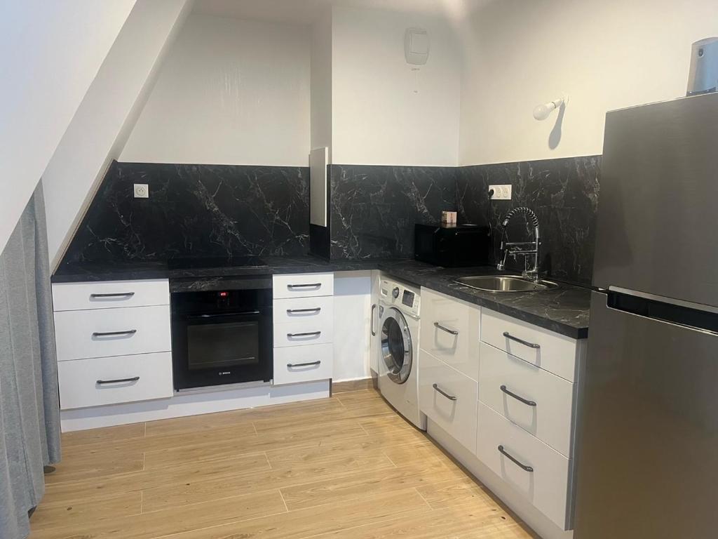 a kitchen with white cabinets and a black counter top at Parisian Skyline Oasis: Panoramic Elegance, Luxury at Your Doorstep in Saint-Ouen