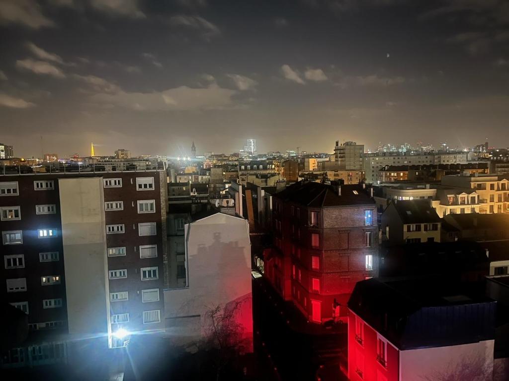 a view of a city at night with buildings at Parisian Skyline Oasis: Panoramic Elegance, Luxury at Your Doorstep in Saint-Ouen