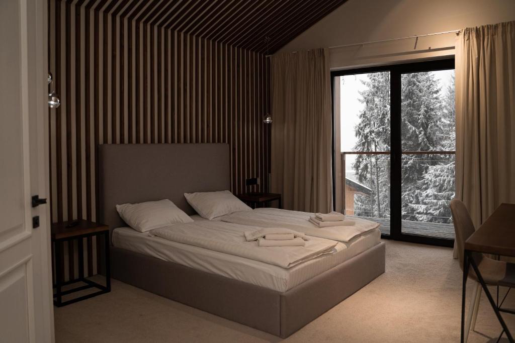 a bedroom with a bed and a large window at Gogodz Chalet Resort in Yablunytsya