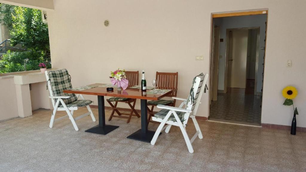 a dining room table with two chairs and a bottle of wine at Apartments ANIMA ex Marin in Podstrana