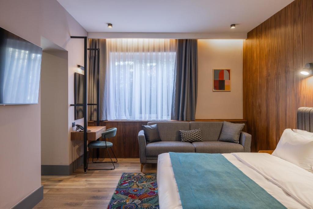um quarto de hotel com uma cama e um sofá em Hotel Square by MARGO em Pristina