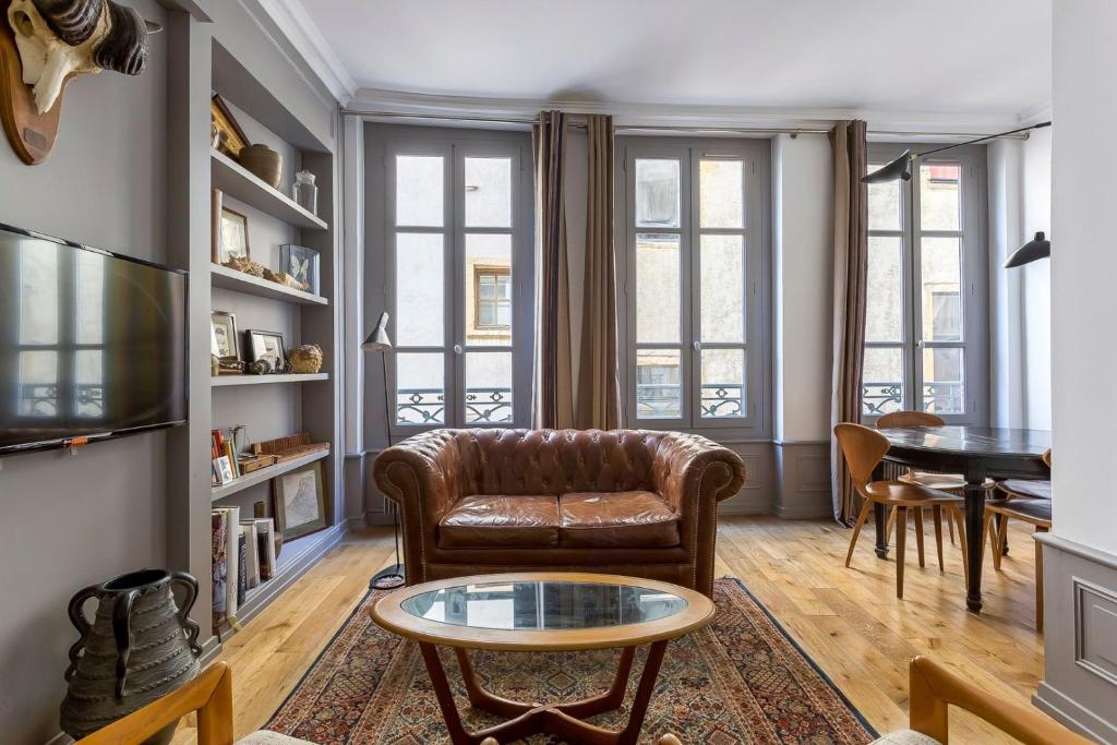 - un salon avec un canapé en cuir et une table dans l'établissement Curiosité - 2 chambres- proche Opéra, à Lyon