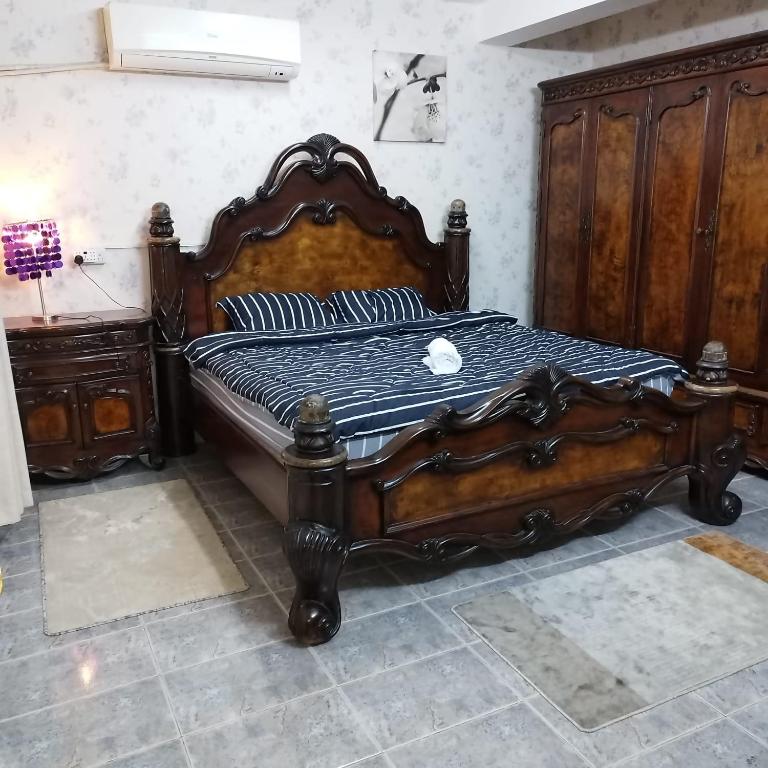 a bedroom with a wooden bed and a wooden dresser at العين الهيلي مصباح ب 2 in Al Ain