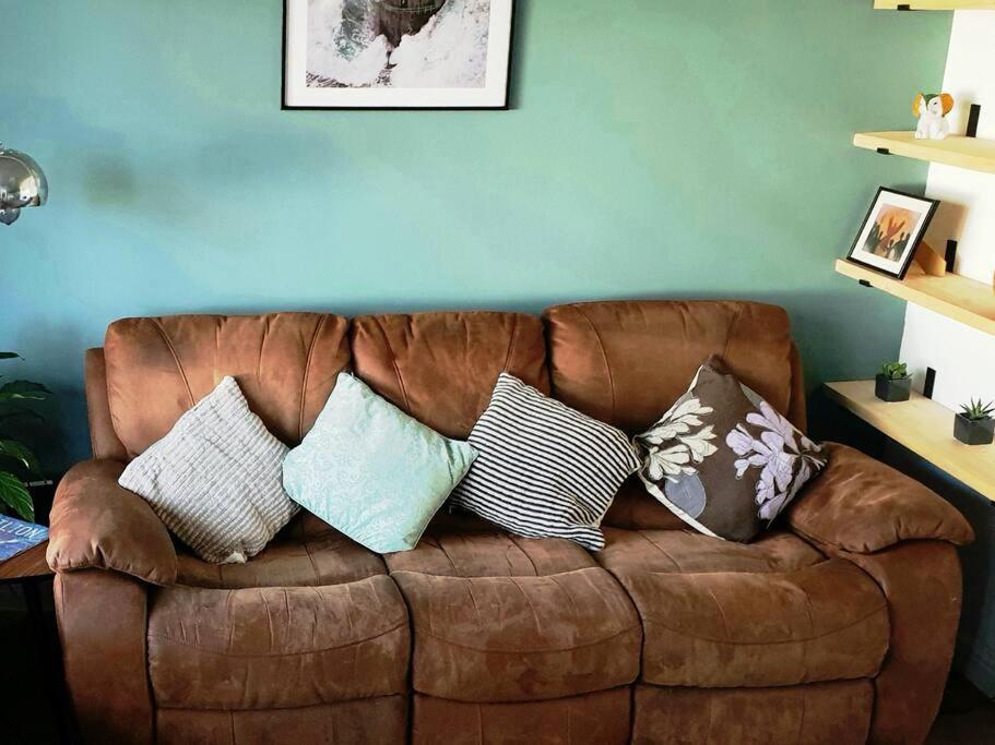 ein braunes Sofa mit Kissen darauf im Wohnzimmer in der Unterkunft Entire house in Sherwood, Nottingham in Nottingham