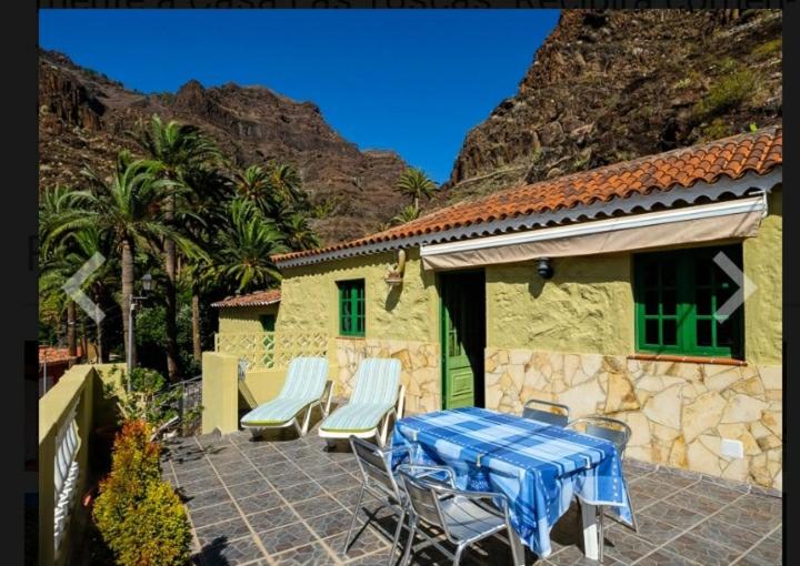 a patio with a table and chairs and a house at Casa las toscas in Calera