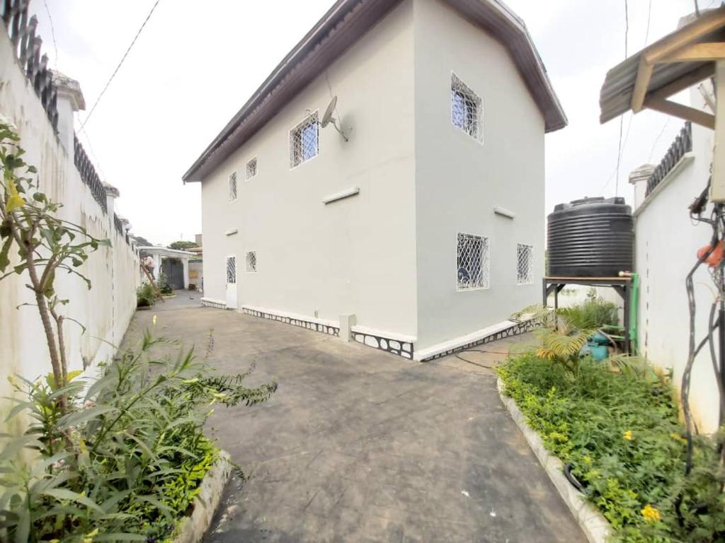 an alleyway leading to a white building at Villa KELIA Biyem-Assi Acacias in Yaoundé