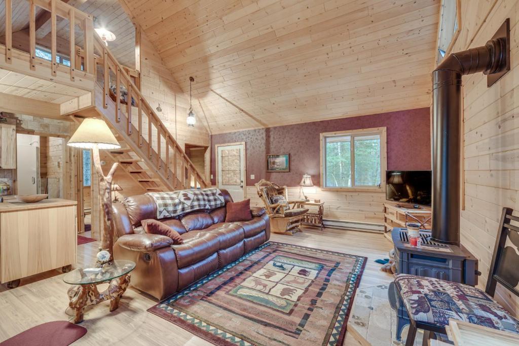 a living room with a couch and a staircase at Barnum Cabin on 30 Acres with Soo Line Trail Access! 