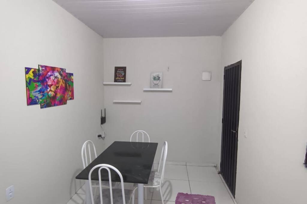 um quarto branco com uma mesa, cadeiras e um quadro em Stúdio Cozy em Palmas