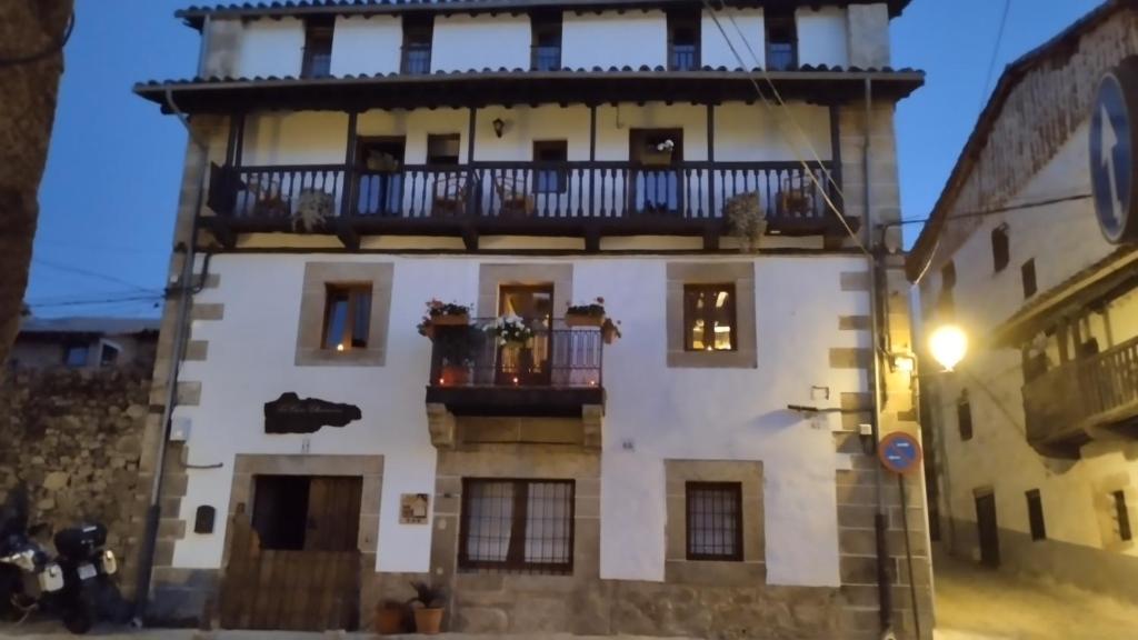 a tall white building with a balcony on it at Hotel La Casa Chacinera in Candelario