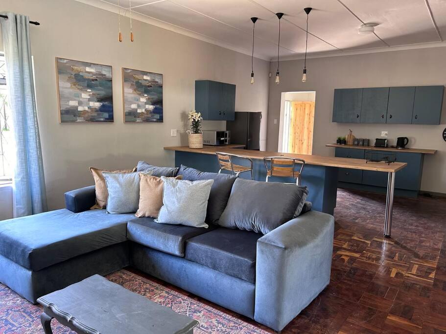 a living room with a blue couch and a kitchen at Lilibeth guesthouse in Parys