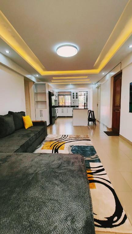 a large living room with a couch and a kitchen at Dora's Apartment in Kampala