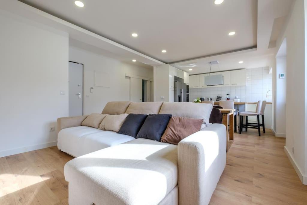 a living room with a white couch and a kitchen at Apartamento T3 em Lisboa/ Queluz in Queluz