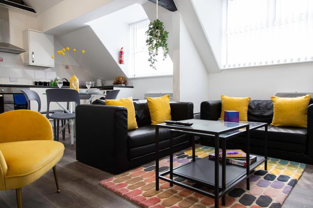 een woonkamer met een zwarte bank en gele kussens bij Bootle, Liverpool Trendy 1Bed Ft in Liverpool
