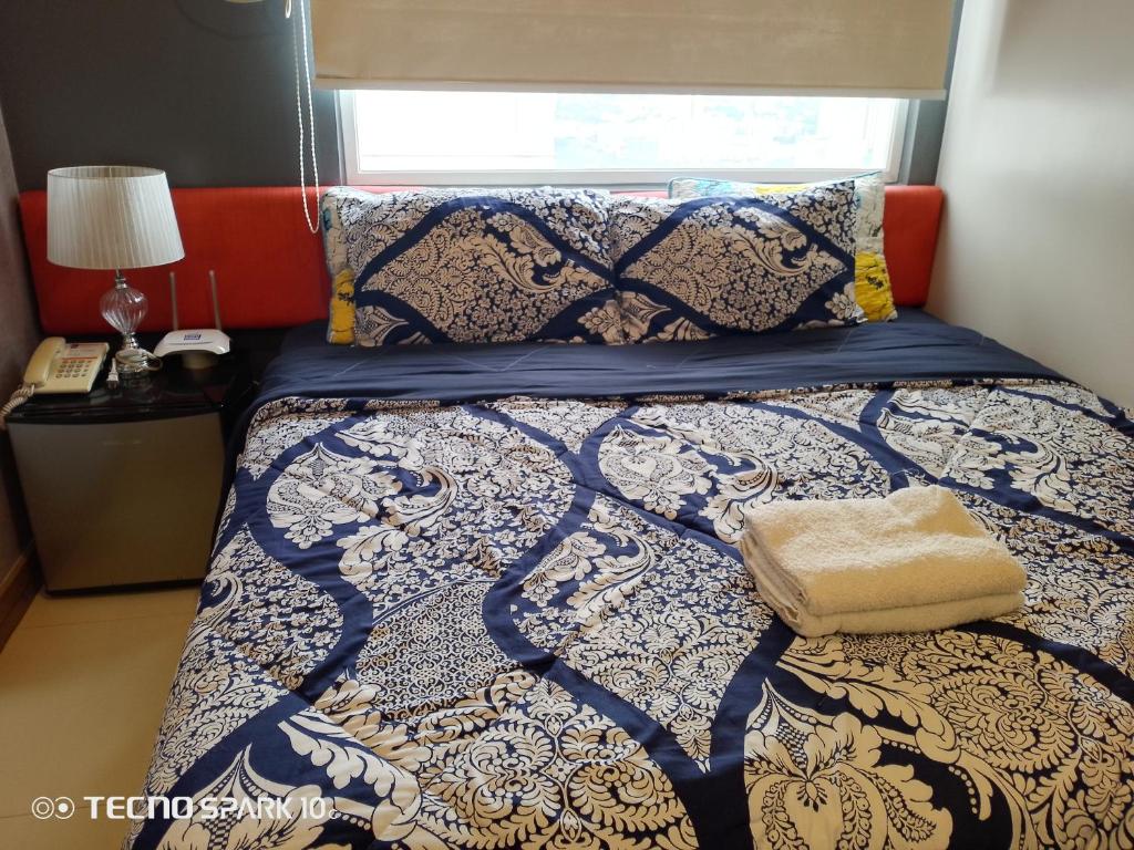 a bed with a blue and white comforter and a window at K2K Place in Manila