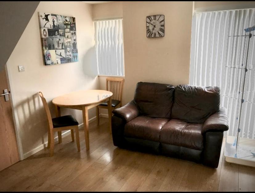 a living room with a leather couch and a table at Rosanne's Rest in Stevenage