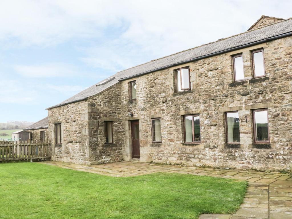 an old stone house with a yard in front of it at Orcaber Farm Barn in Austwick