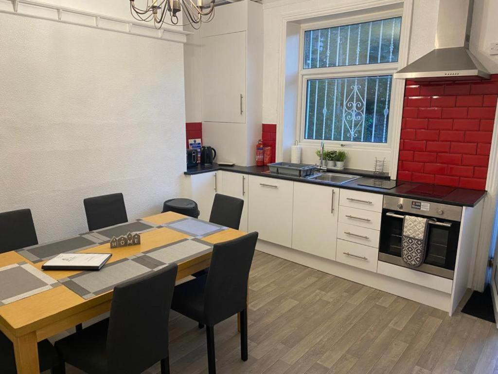 a kitchen with a dining table and a kitchen with a red wall at Spacious 4 Bedroom Townhouse in Leeds