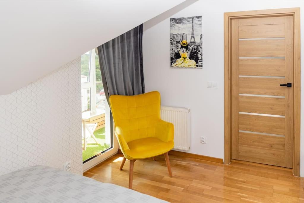 a yellow chair in a bedroom with a window at Apartament na Górnej in Puńsk