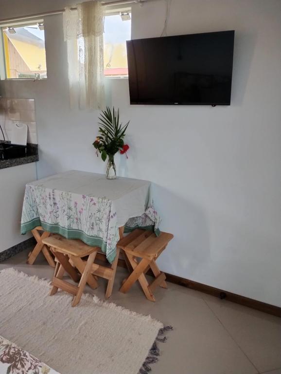 a dining room with a table and chairs and a tv at Vila Sabará in Pinheira