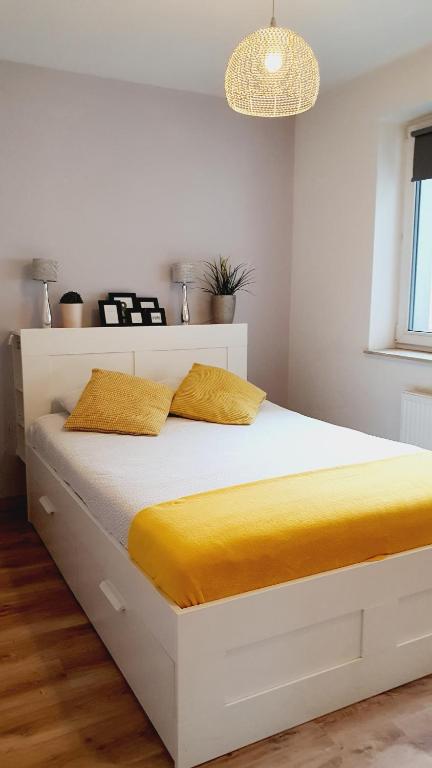 a white bed with yellow sheets in a bedroom at Good Time Apartments Strzelecka C in Poznań