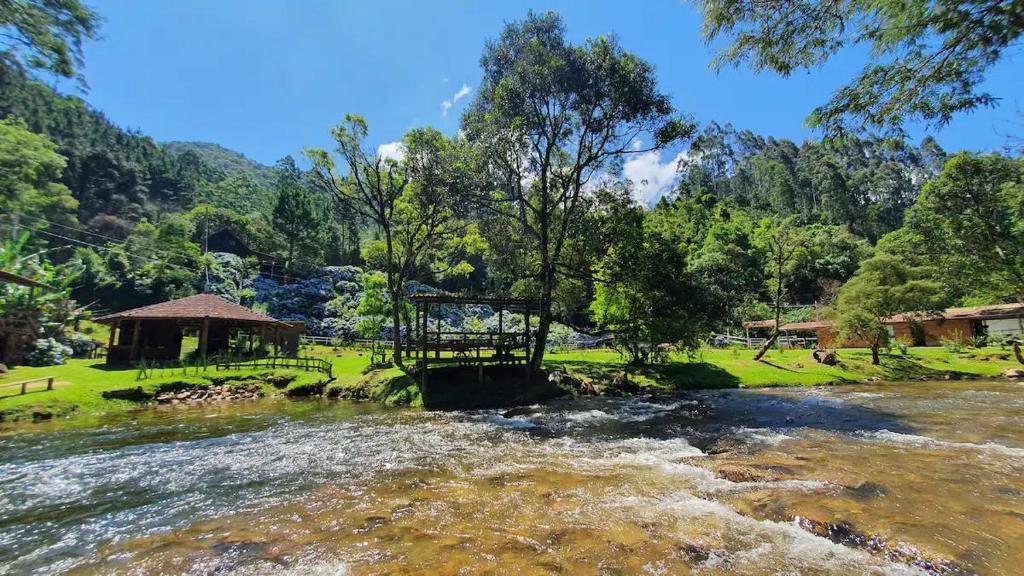 einen Fluss mit einer Brücke neben einem Wald in der Unterkunft Chalé Villa das Hortênsias in Annitapolis