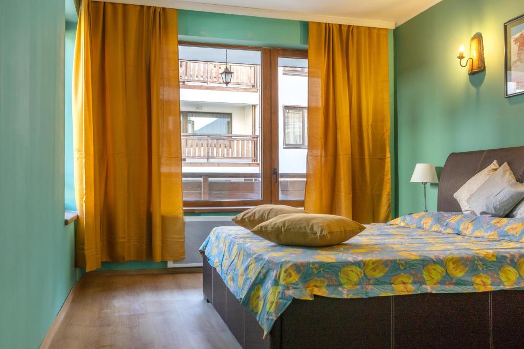 een slaapkamer met een bed met gele gordijnen en een raam bij Cedar Lodge III 2 BDRM Flat B12 in Bansko